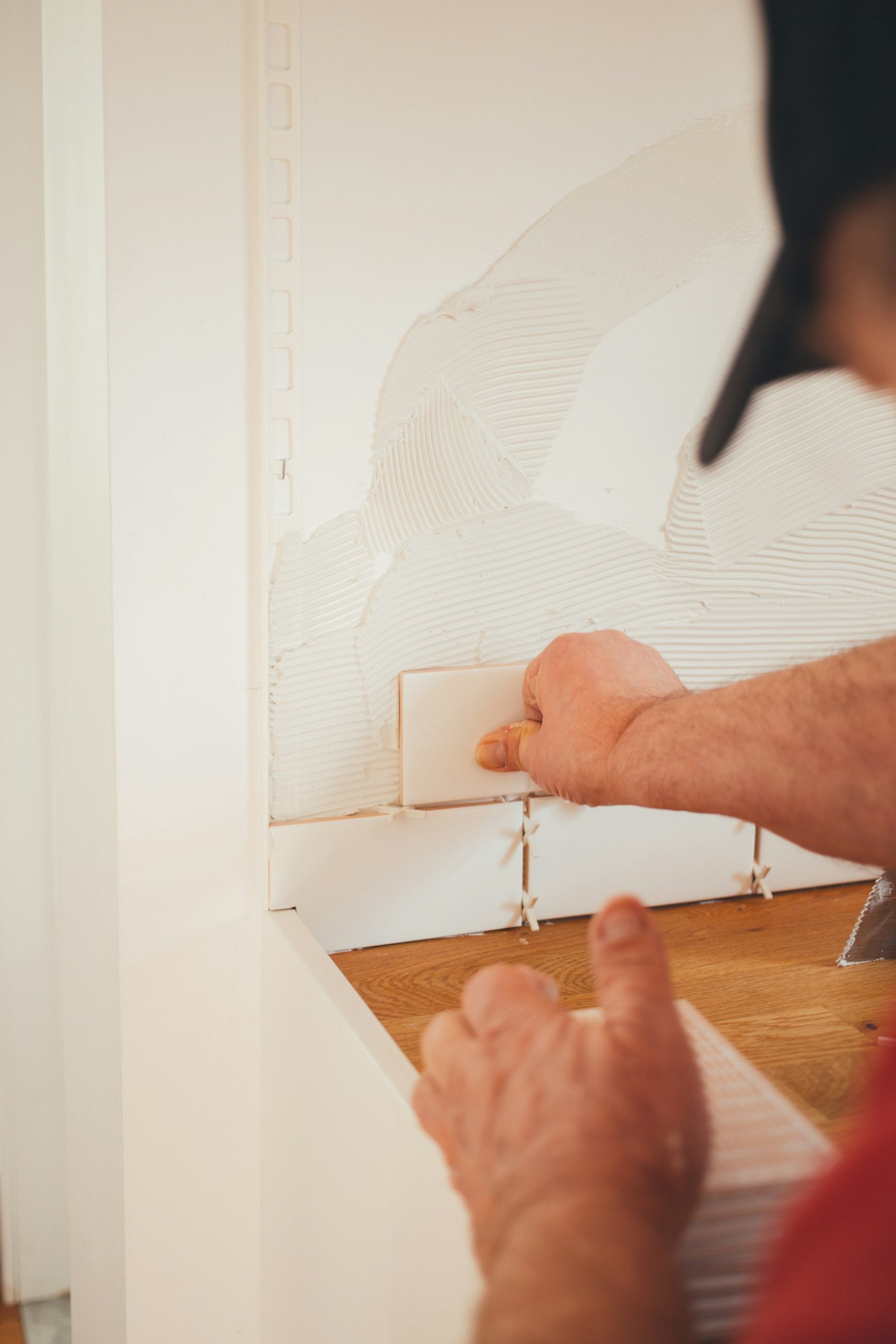 A craftsman setting subway tile by hand on a bathroom wall