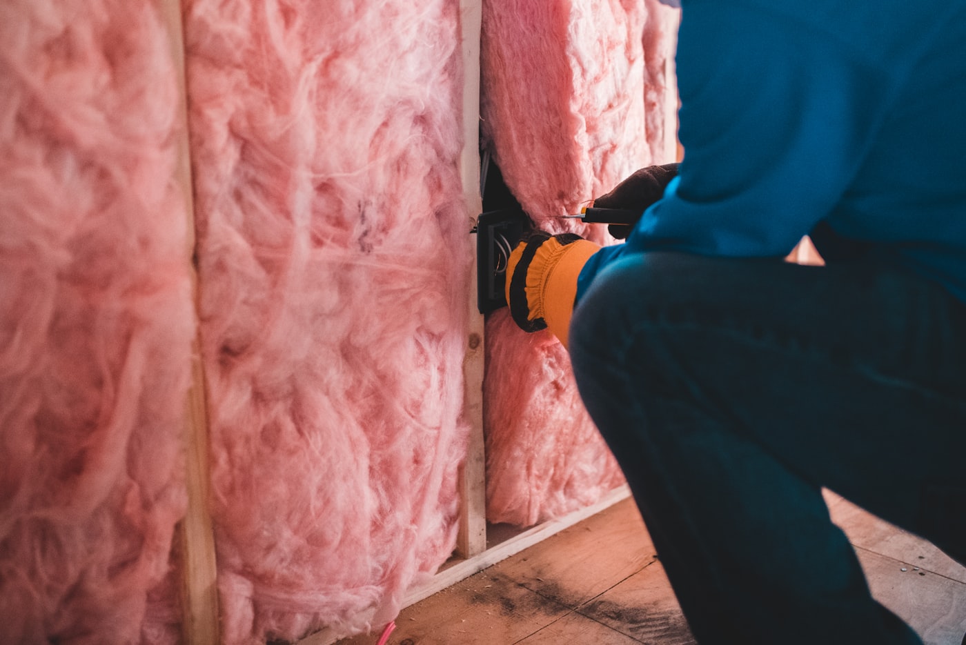 A crew member installing wall insulation during a framing stage